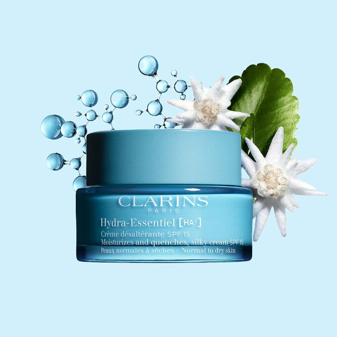 Pakkebilde av Clarins Hydra-Essentiel SPF15 i nærheten av noen edelweissblomster mot en blå bakgrunn.
