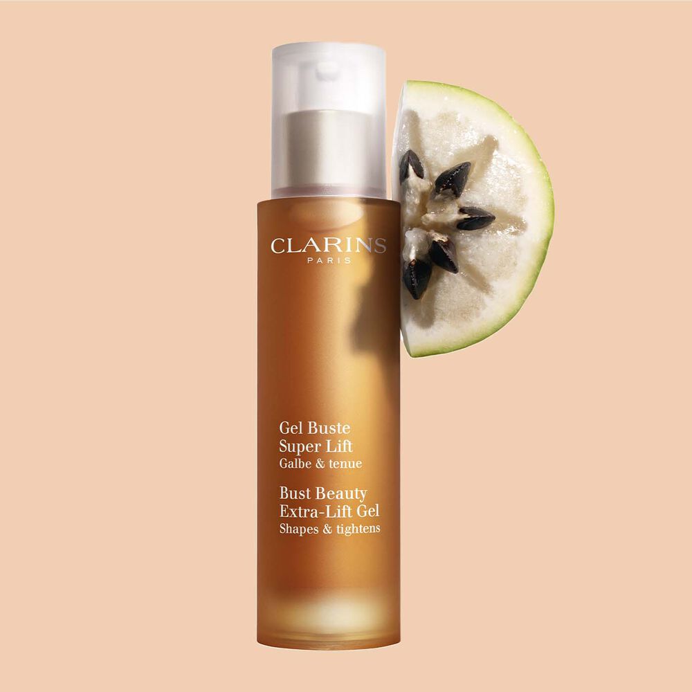 Pakkebilde av en flaske med Clarins Bust Beauty Extra-Lift Gel i nærheten av en bit stjerneeple mot en ferskenfarget bakgrunn.