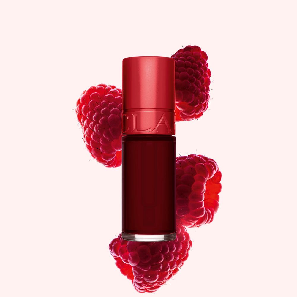 Packshot av Clarins Dark Red Water Lip Stain i nyanse 9, plassert ved siden av bringebær på en lys rosa bakgrunn.
