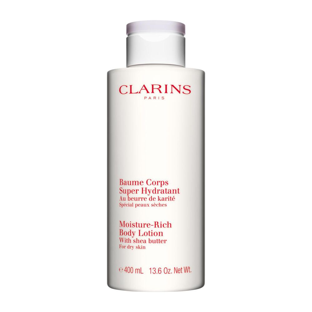 Pakkebilde av en flaske med Clarins Moisture-Rich Body Lotion i n&aelig;rheten av noen shean&oslash;tter mot en hvit bakgrunn.