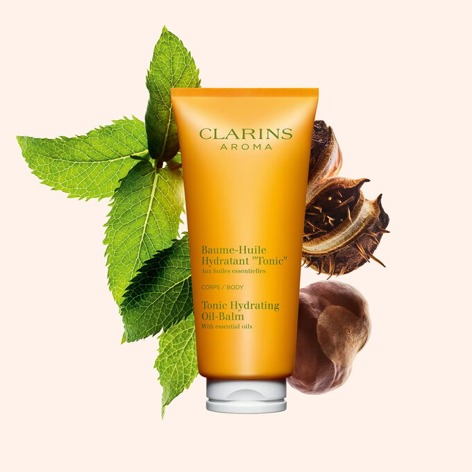 Pakkebilde av en tube med Clarins Tonic Hydrating Oil-Balm, i n&aelig;rheten av mynteblader og sheafr&oslash; mot en ferskenfarget bakgrunn.