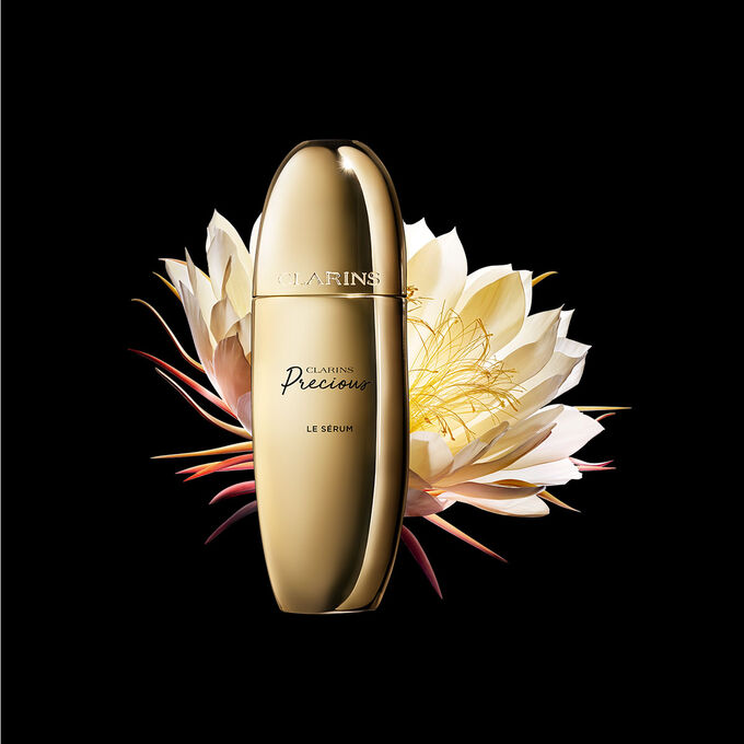 Pakkebilde av Clarins Precious Serum i n&aelig;rheten av blomsten nattens dronning mot en m&oslash;rk bakgrunn.
