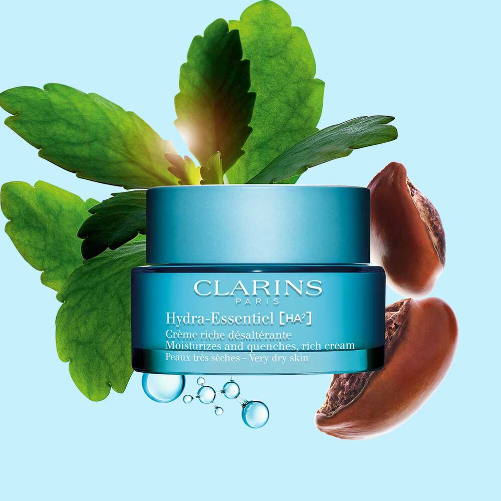 Pakkebilde av Clarins Hydra-Essentiel Rich Cream i nærheten av noen sheanøtter og kalanchoeblad mot en blå bakgrunn.
