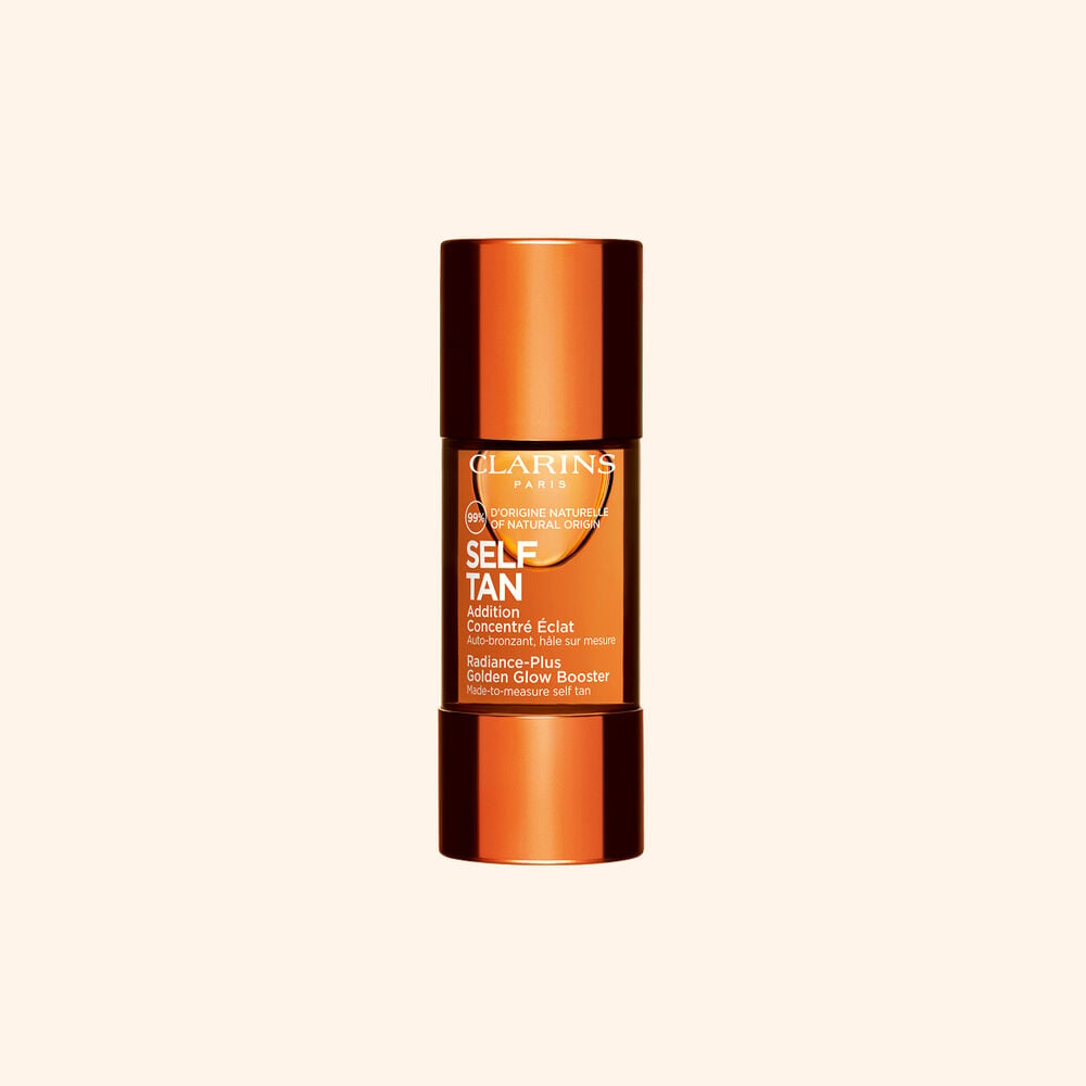 Clarins selvbrunende glow booster-flaske vist mot beige bakgrunn for en solkysset str&aring;lende hudrutine.