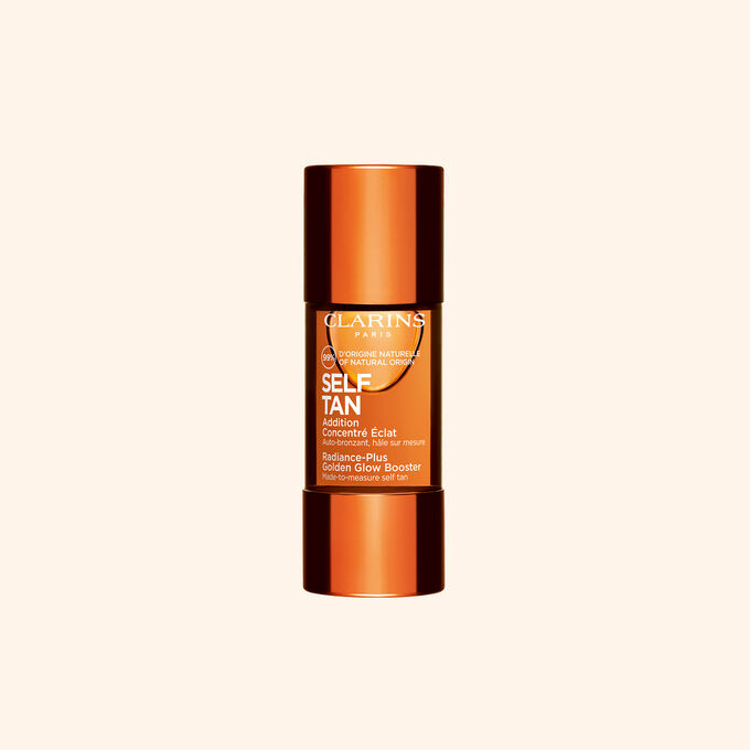 Clarins selvbrunende glow booster-flaske vist mot beige bakgrunn for en solkysset str&aring;lende hudrutine.