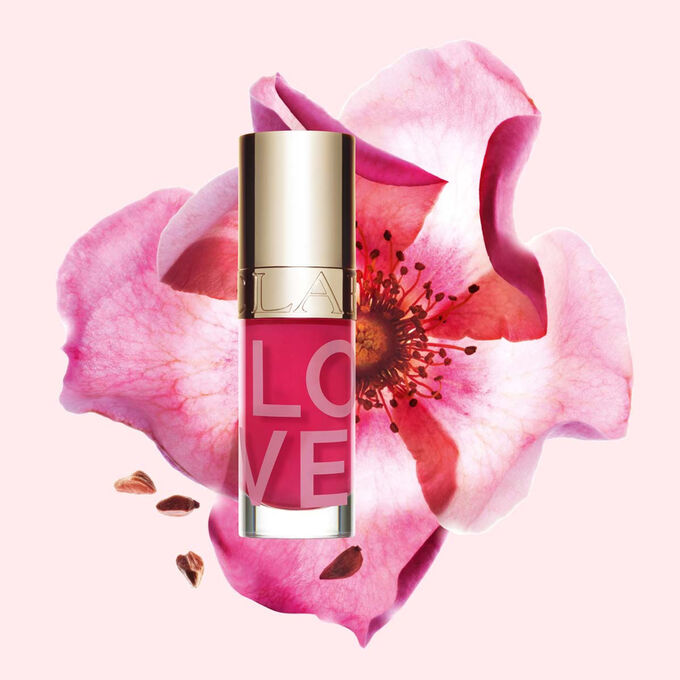 Produktbilde av Lip Oil Limited Edition Love Collection foran en rose p&aring; en lys rosa bakgrunn som fremhever den livfulle fargen.