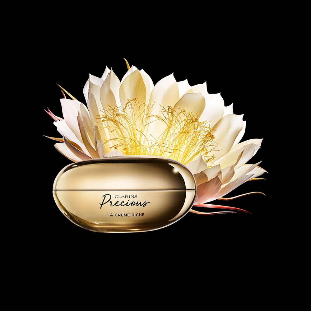 Pakkebilde av Clarins Precious Rich Cream i nærheten av blomsten nattens dronning mot en mørk bakgrunn.