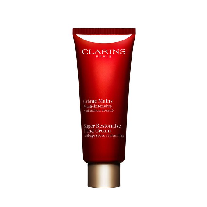Pakkebilde av en flaske med Clarins Super Restorative Hand Cream i n&aelig;rheten av noen harunganablader mot en rosa bakgrunn.