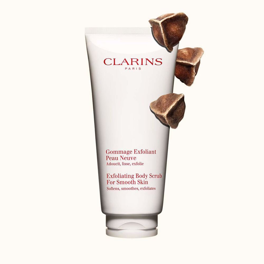 Pakkebilde av Clarins Exfoliating Body Scrub for Smooth Skin plassert ved siden av moringanøtter mot en lys beige bakgrunn