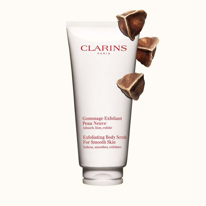 Pakkebilde av Clarins Exfoliating Body Scrub for Smooth Skin plassert ved siden av moringanøtter mot en lys beige bakgrunn