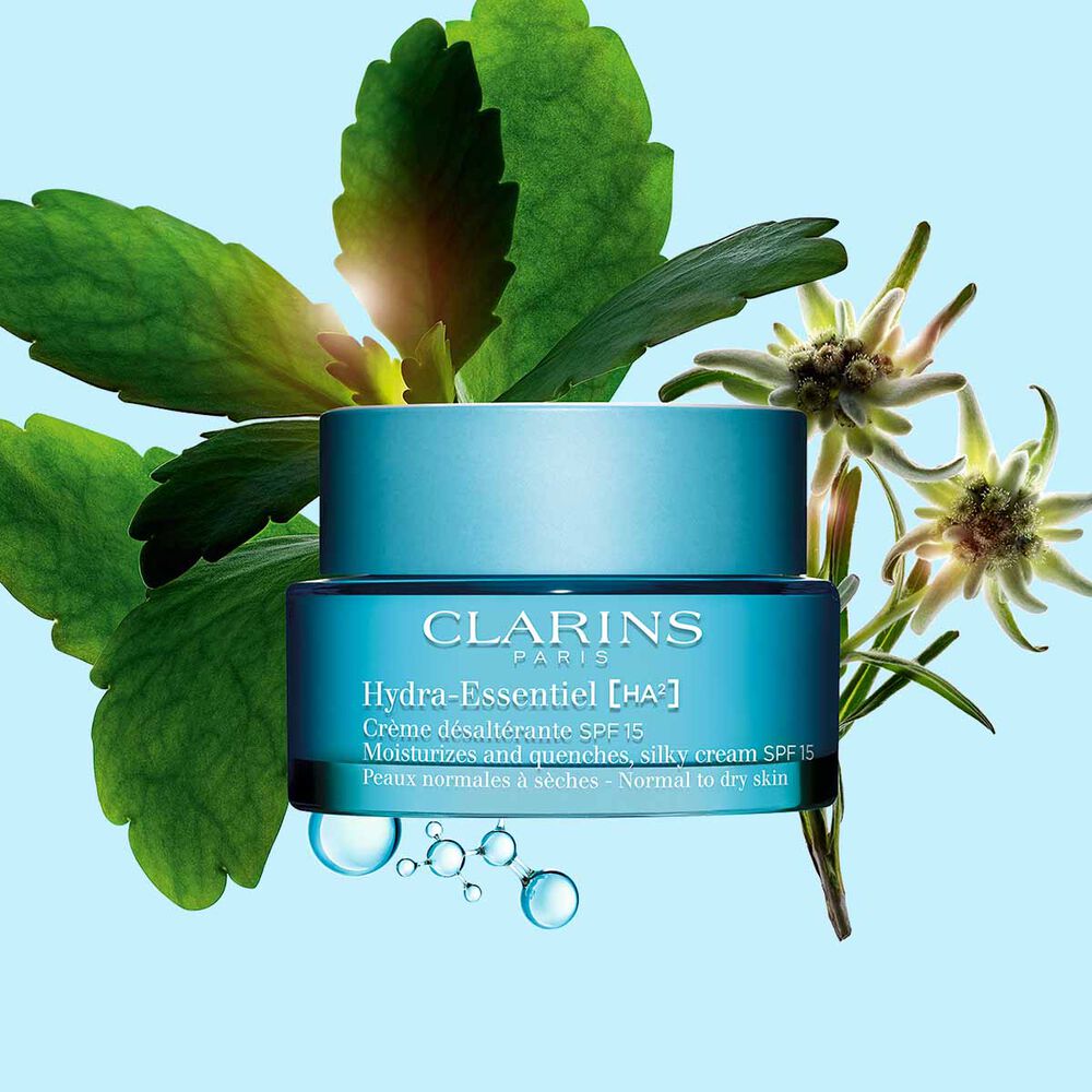 Pakkebilde av Clarins Hydra-Essentiel SPF15 i nærheten av noen edelweissblomster mot en blå bakgrunn.