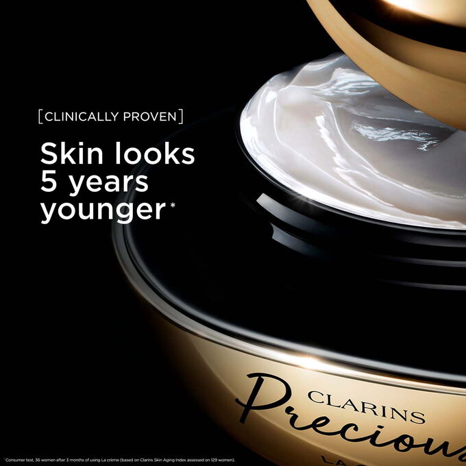 Pakkebilde av Clarins Precious Soft Cream mot en m&oslash;rk bakgrunn med tekst som fremhever kraften til &aring; f&aring; huden til &aring; se fem &aring;r yngre ut