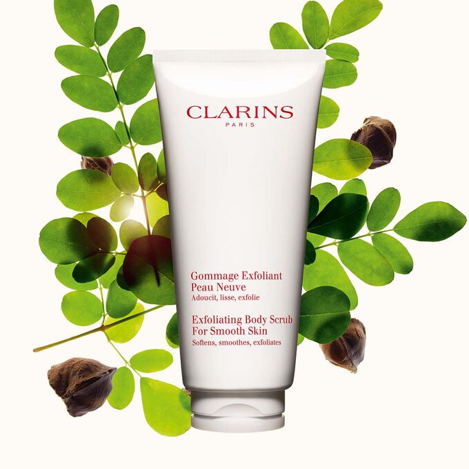 Pakkebilde av Clarins Exfoliating Body Scrub for Smooth Skin plassert ved siden av moringan&oslash;tter mot en lys beige bakgrunn
