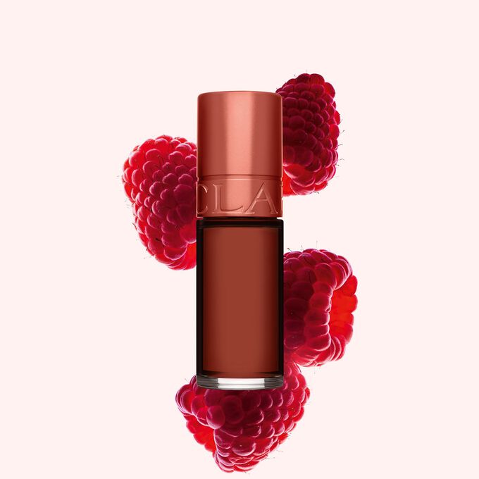Packshot av Clarins Brown Water Lip Stain i nyanse 13, plassert ved siden av bringeb&aelig;r p&aring; en lys rosa bakgrunn.