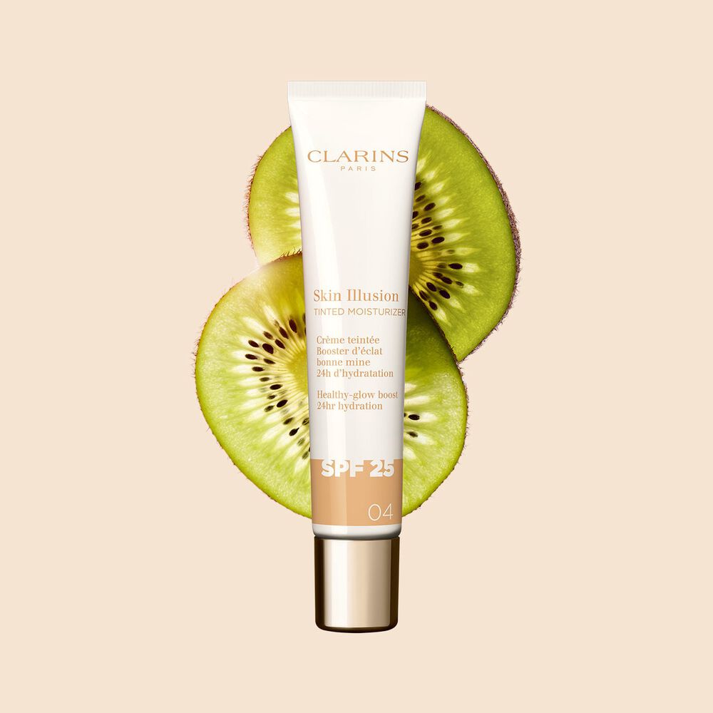 Packshot av Tinted Moisturizer med SPF for medium hudtone 04, plassert ved siden av kiwi-skiver på en beige bakgrunn.