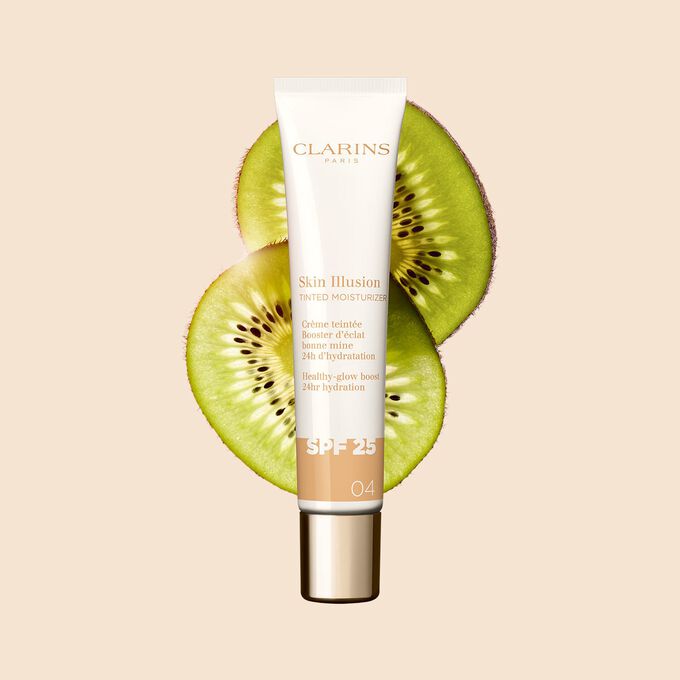 Packshot av Tinted Moisturizer med SPF for medium hudtone 04, plassert ved siden av kiwi-skiver på en beige bakgrunn.