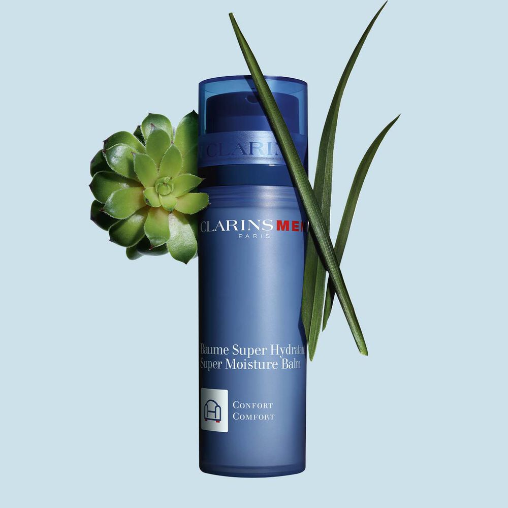 Pakkebilde av en pumpeflaske med ClarinsMen Super Moisture Balm i nærheten av gymnena og marigress mot en blå bakgrunn.