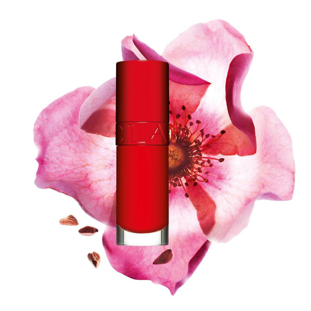 Packshot av Clarins Lip Comfort Oil i Iconic Red, plassert ved siden av en nyperoseblomst på en svart-rød bakgrunn.