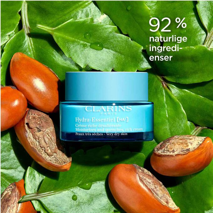 Pakkebilde av Clarins Hydra-Essentiel 23 Rich Cream blant blader og sheanøtter som fremhever at den inneholder 92 % naturlige ingredienser