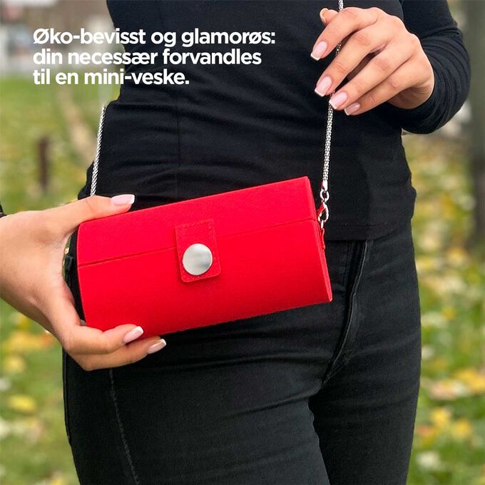 Nærbilde av necessæren, som viser dens røde design og evnen til å forvandle seg til en mini-veske med en stropp.
