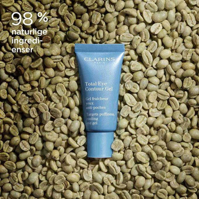 Tube med Clarins Total Eye Contour Gel blant kaffebønner for å illustrere det naturlige opphavet til ingrediensene i produktet.