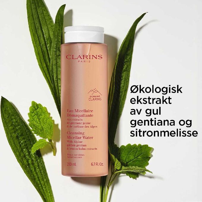 Packshot av flasken med rensende micell&aelig;rvann foran sitronmelisse og gul gentiana for &aring; fremheve hovedingrediensen.