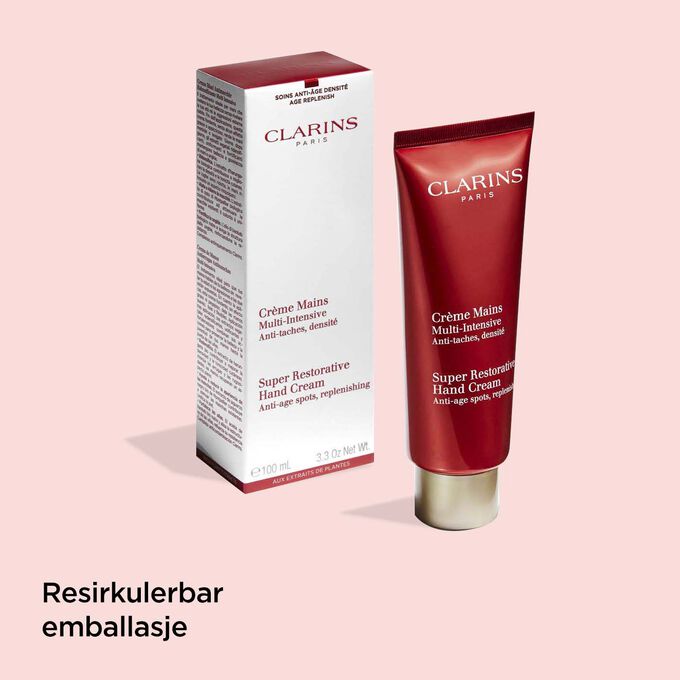 Tube med Clarins Super Restorative Hand Cream ved siden av emballasjen for å illustrere at emballasjen er laget av resirkulerte materialer.
